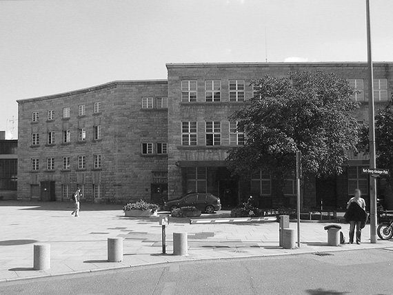 An den Posttrakt schließt ein kleiner konkaver Bürotrakt an, mit dem die Fassade ausschwingt